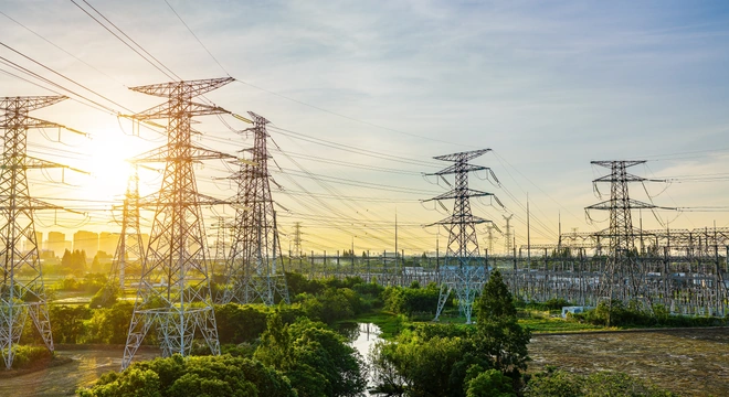 High-voltage transmission towers and substation at sunrise