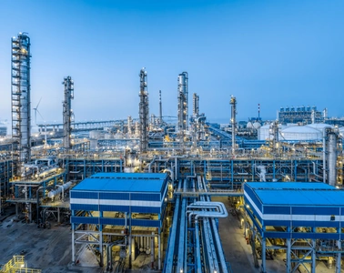 Oil and gas processing facility with refinery towers and pipelines under a blue sky