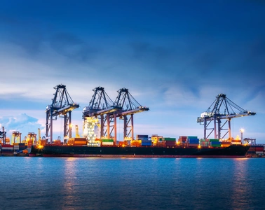 Container port with ship-to-shore cranes at dusk