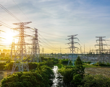 High-voltage transmission towers and substation at sunrise