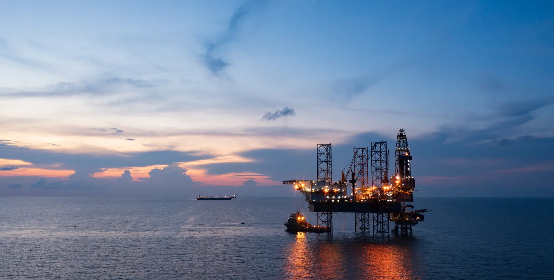 Offshore oil and gas production platform at sea at sunset