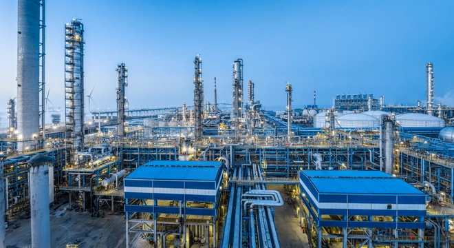 Oil and gas processing facility with refinery towers and pipelines under a blue sky