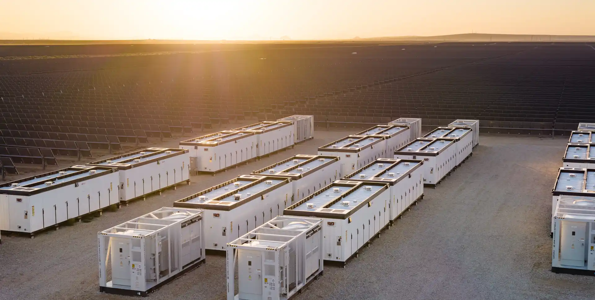 Battery energy storage containers at a solar power plant at sunset