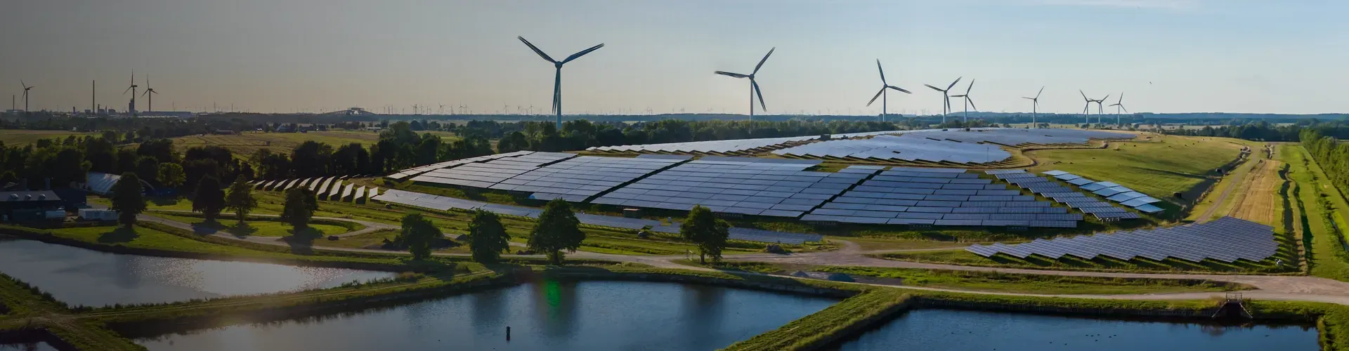 Solar and Wind Farm in rural area with green trees and grass