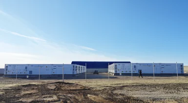 Grid-forming battery energy storage containers at a renewable energy site under a blue sky