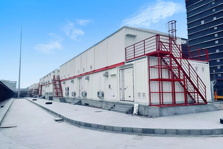 Row of E-House modules with red access stairs alongside a data center building