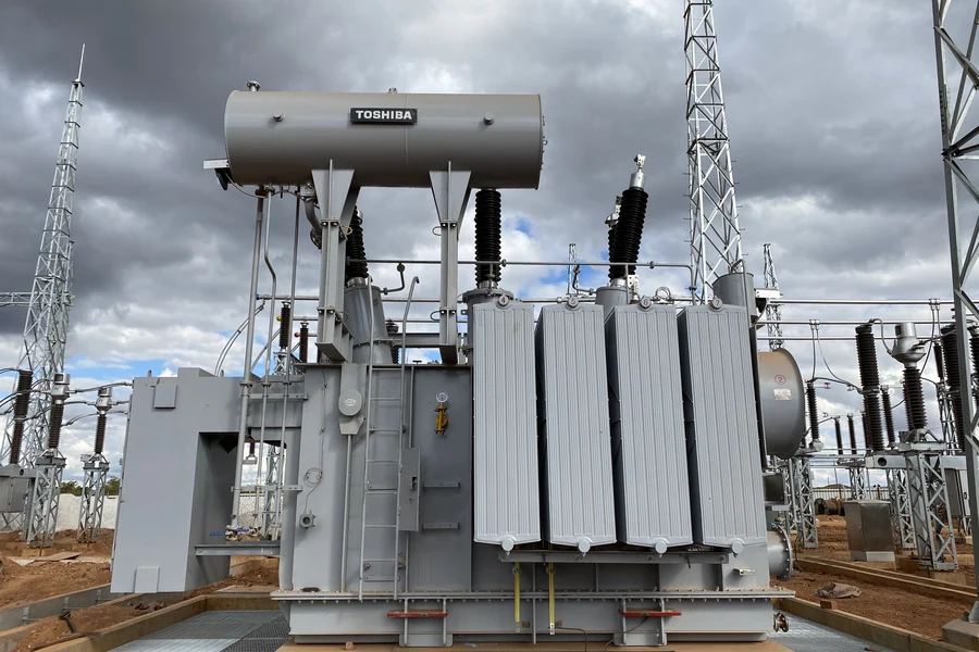 Power transformer installed at an outdoor transmission substation under a cloudy sky