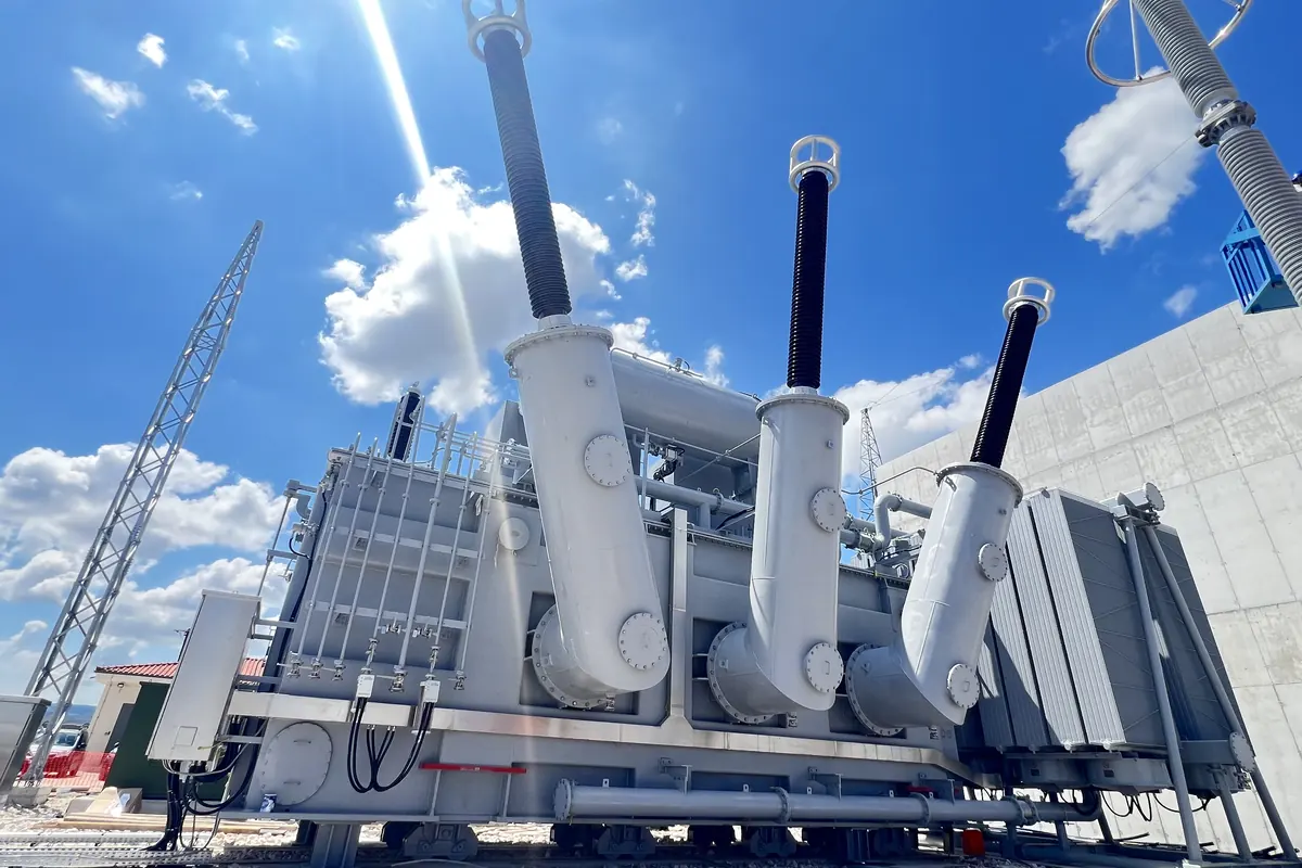 Large outdoor power transformer with high-voltage bushings installed at a substation under a blue sky
