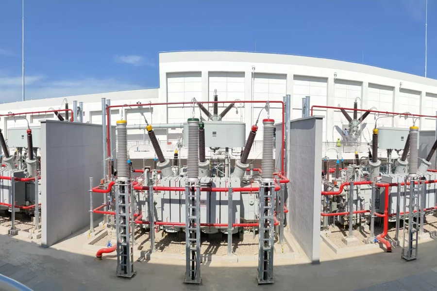Power transformers with red fire-protection piping at a refinery substation